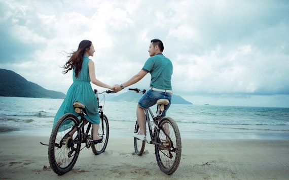 海辺の自転車に乗るカップル